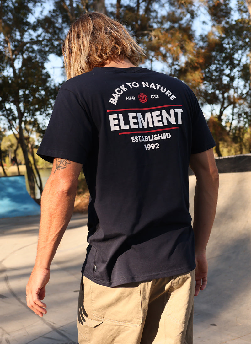 A man wearing a black t-shirt with 'Element' branding at a skate park.